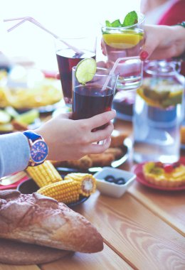 Ahşap masada otururken birlikte yemek yiyen bir grup insanın üst düzey görüntüsü. Masada yemek var. İnsanlar fast food yiyor..
