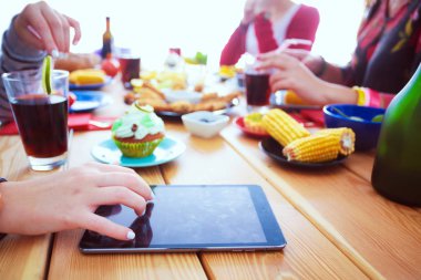 Ahşap masada otururken birlikte yemek yiyen bir grup insanın üst düzey görüntüsü. Masada yemek var. İnsanlar fast food yiyor..