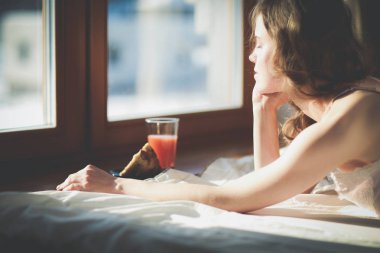 Pencere yakınındaki erken sabah yatakta yatan kadın.