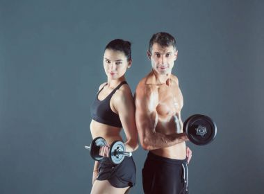 Atletik erkek ve kadın ile bir dumbells. Kişisel fitness eğitmeni. Kişisel eğitim.