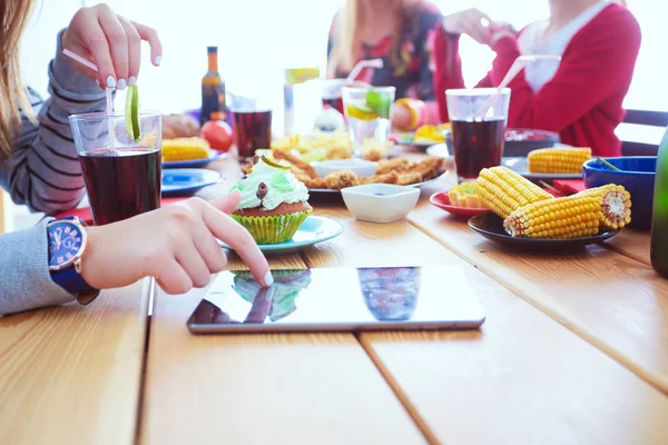 Ahşap masada otururken birlikte yemek yiyen bir grup insanın üst düzey görüntüsü. Masada yemek var. İnsanlar fast food yiyor..