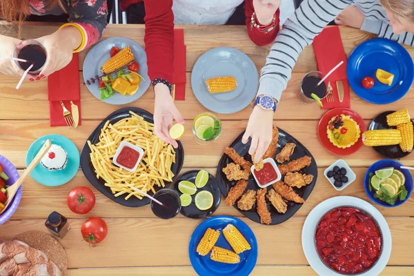 Vue du dessus du groupe de personnes qui dînent ensemble tout en étant assis à une table en bois. De la nourriture sur la table. Les gens mangent fast food. — Photo