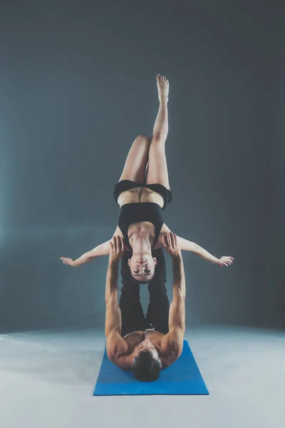 Young couple practicing acro yoga on mat in studio together. Acroyoga. Couple yoga. Partner yoga.