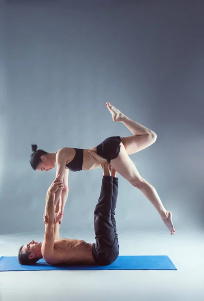 Pasangan muda berlatih akroyoga di atas tikar di studio bersama-sama. Acroyoga. Beberapa yoga. Partner yoga . — Stok Foto