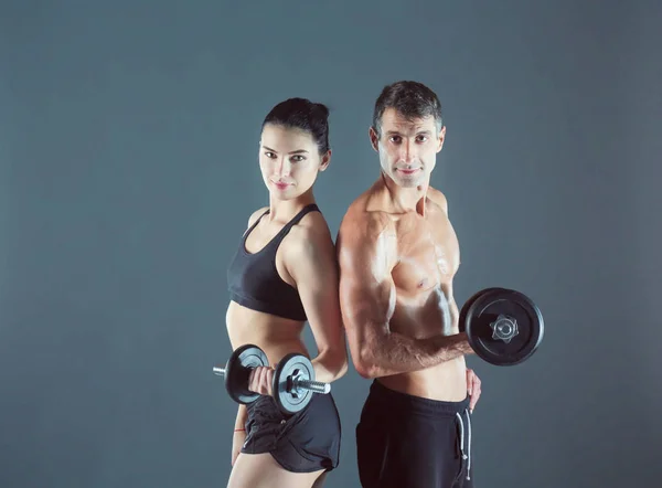 Athletic man and woman with a dumbells. Personal fitness instructor. Personal training. — Stock Photo, Image