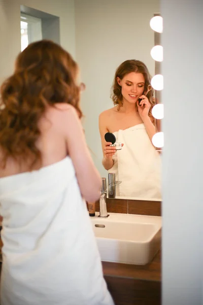 Mujer joven de pie en el baño con teléfono . — Foto de Stock