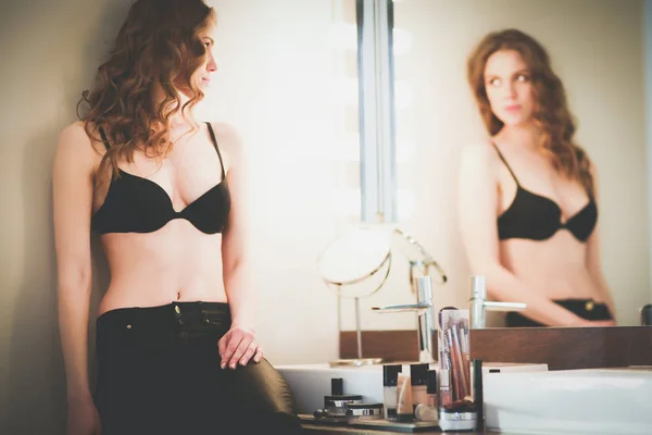 Jovem mulher olhando-se no espelho no banheiro . — Fotografia de Stock