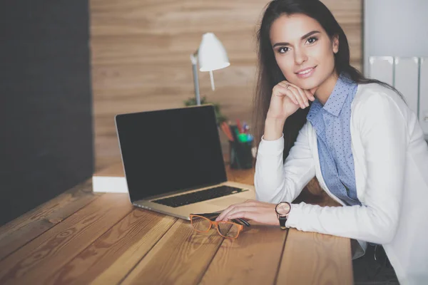 Jeune femme travaillant assise à un bureau. — Photo