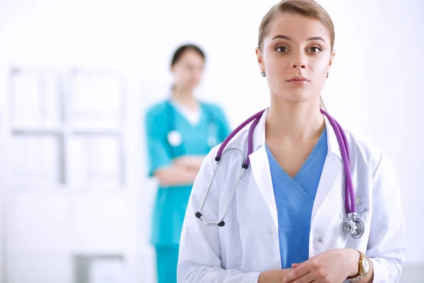 若いです女性医師の肖像とともに医療聴診器でホワイトコートに立って病院 — ストック写真