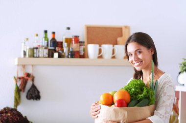 Elinde sebzeli alışveriş torbası tutan genç bir kadın.