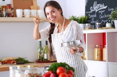 Mutfakta ahşap kaşıkla yemek pişiren kadın