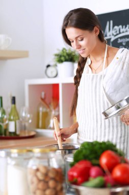 Mutfakta ahşap kaşıkla yemek pişiren kadın