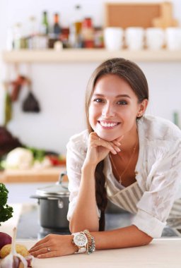 Mutfakta yemek yapmak için tablet bilgisayar kullanan genç bir kadın.