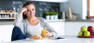 Mutfakta sobanın yanında duran genç bir kadın. Mutfakta yemek pişiren kadın..