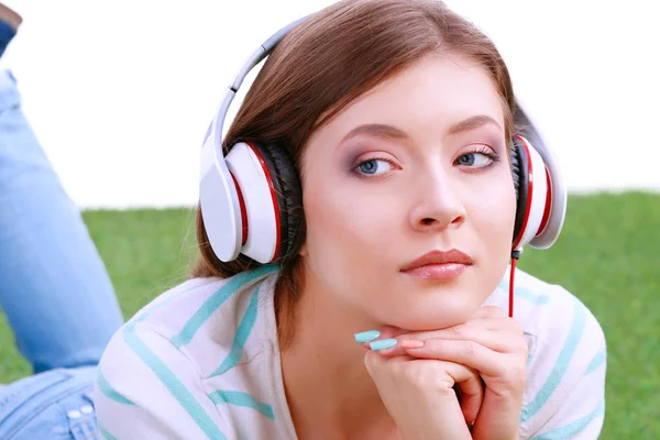 Mujer joven escuchando la música, acostada sobre hierba verde —  Fotos de Stock