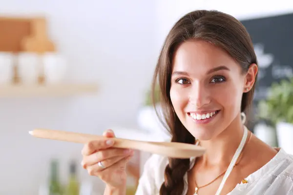 Mujer cocinera en cocina con cuchara de madera —  Fotos de Stock