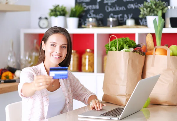 Smiling woman online shopping using tablet and credit card in kitchen — Stock Photo, Image