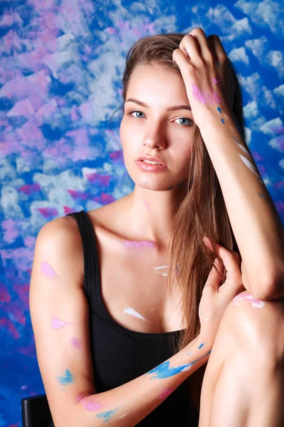 Mujer hermosa joven sentada cerca de la pared de pintura — Foto de Stock