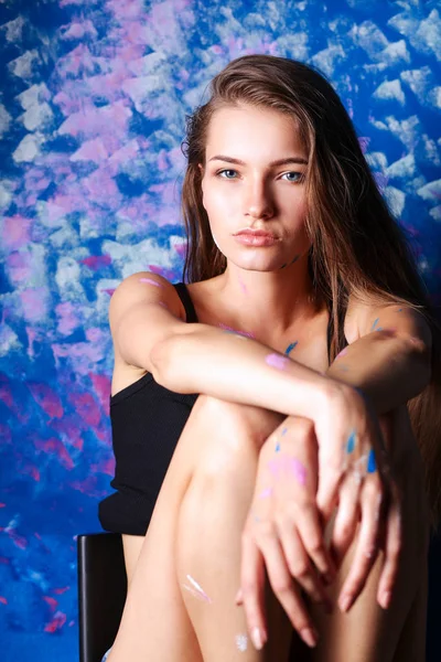 Fiatal gyönyörű nő ül festészet fal közelében — Stock Fotó