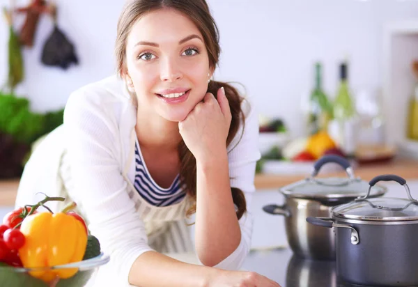 Mujer joven sentada cerca de escritorio en la cocina —  Fotos de Stock