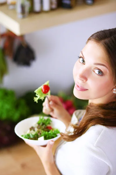 Mujer joven comiendo ensalada y sosteniendo una ensalada mixta — Foto de Stock