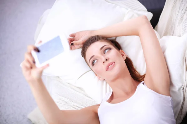 Jeune belle femme assise sur le canapé dans sa chambre en utilisant le téléphone — Photo