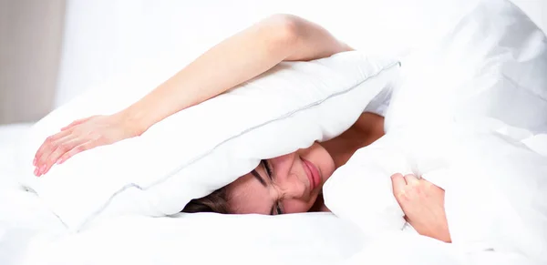 Femme couchée sur le lit et fermant ses oreilles avec un oreiller — Photo