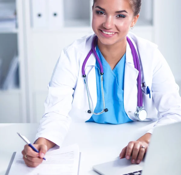 Female doctor sitting on the desk and working a laptop in hospital — Stock Photo, Image