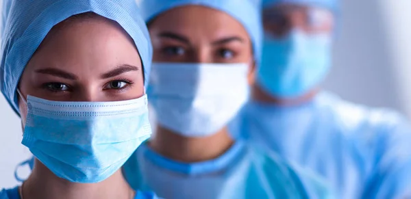 Équipe de chirurgiens, portant des uniformes de protection, des casquettes et des masques — Photo