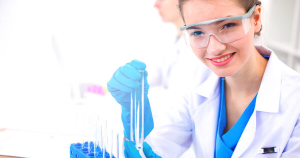 Woman researcher is surrounded by medical vials and flasks, isolated on white background