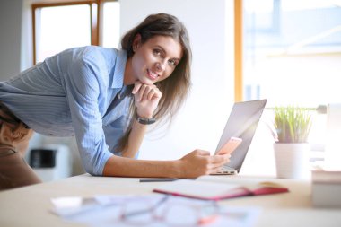 Ofis masasında oturan ve cep telefonuyla konuşan genç ve güzel bir iş kadını. İş kadını