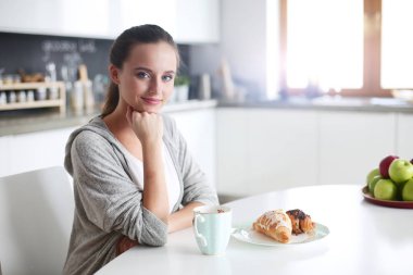 Mutfak masasında tatlı kruvasan ile çay içme kadın.