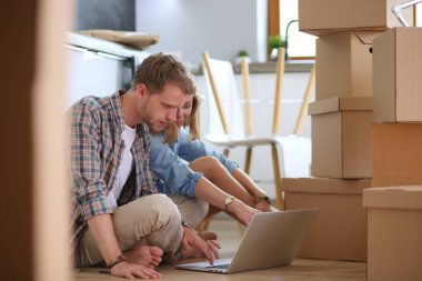 Genç bir çift yeni ev içinde hareket. Oturma ve açma sonra rahatlatıcı. Bir şey üstünde laptop arıyorum. Genç Çift