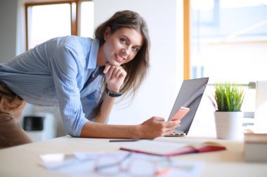 Ofis masasında oturan ve cep telefonuyla konuşan genç ve güzel bir iş kadını. İş kadını