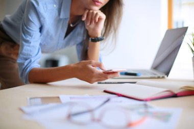 Ofis masasında oturan ve cep telefonuyla konuşan genç ve güzel bir iş kadını. İş kadını