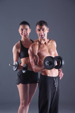 Atletik erkek ve kadın ile bir dumbells. Kişisel fitness eğitmeni. Kişisel eğitim.