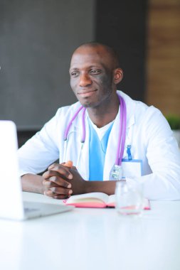 Masada dizüstü bilgisayarla çalışan genç bir Afrikalı doktor. Doktor bey. İşyeri