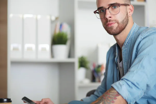 Jonge man met behulp van een telefoon en werken op een laptop. Student SMS op de telefoon. — Stockfoto