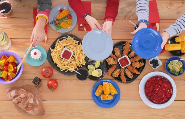 Vue du dessus du groupe de personnes qui dînent ensemble tout en étant assis à une table en bois. De la nourriture sur la table. Les gens mangent fast food. — Photo