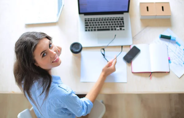 Giovane donna seduta al tavolo dell'ufficio, guardando lo schermo del computer portatile. Giovane donna — Foto Stock