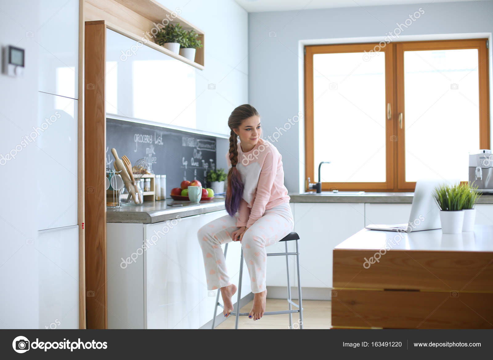 Joven mujer sentada en la mesa en la cocina — Foto de stock ... Joven mujer sentada en la mesa en la cocina — Foto de stock ...