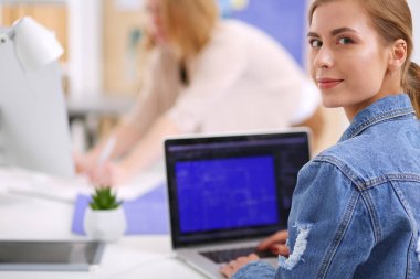 İki genç kadın masada enstrümanlar, planlar ve dizüstü bilgisayarlarla oturuyor..