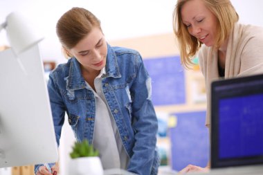 Masanın yanında duran iki genç kadın enstrüman, plan ve dizüstü bilgisayarla.