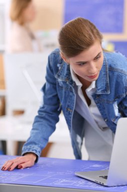 Masanın yanında duran iki genç kadın enstrüman, plan ve dizüstü bilgisayarla.