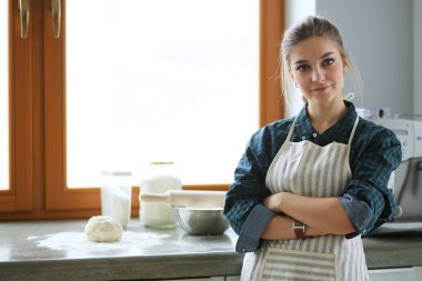 Mutfakta sobanın yanında duran genç bir kadın. .