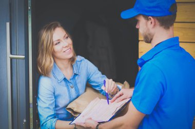 Mavi üniformalı gülümseyen kurye servis konseptine paket kutusu teslim eden teslimatçı. Mavi üniformalı gülümseyen teslimatçı.