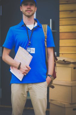 Mavi üniformalı gülümseyen kurye servis konseptine paket kutusu teslim eden teslimatçı. Mavi üniformalı gülümseyen teslimatçı.