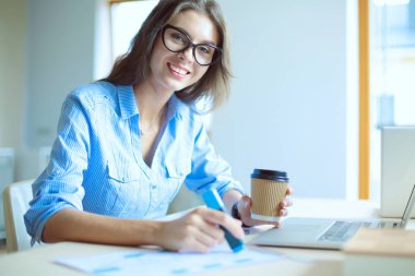 Ofis masasında oturan genç bir kadın dizüstü bilgisayar ekranına bakıyor. Genç kadın.