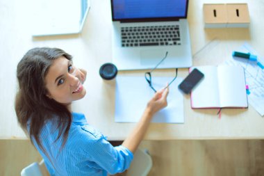 Ofis masasında oturan genç bir kadın dizüstü bilgisayar ekranına bakıyor. Genç kadın.