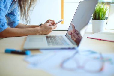 Ofis masasında oturan ve cep telefonuyla konuşan genç ve güzel bir iş kadını. İş kadını